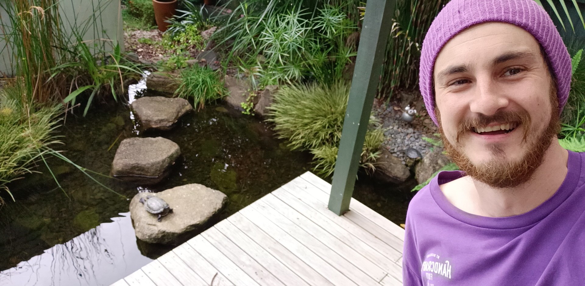 Kieran standing beside a landscaped pond and garden